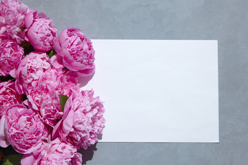 white paper on a gray background and a bouquet of pink peonies