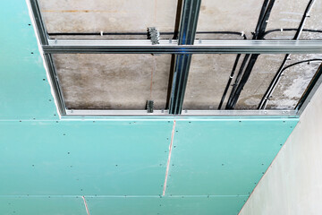 Steel studs are used to frame the ceiling in a plasterboard commercial building. Drywall installation process