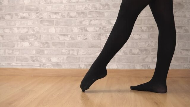Close up of the feet of an unrecognizable beautiful young woman dancer stretching in the studio for a classical dance training session