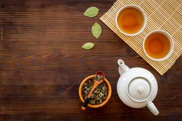 Ceramic white teapot and black tea in two cups, top view