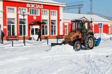 Samara, Chapaevsk, Russia-February.20.2018: Snow plow truck cleaning forecourt area streets Winter snow removal concept city landscape background horizontal - obrazy, fototapety, plakaty