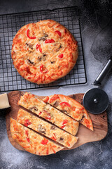 Pizza flatbread on a thick dough base with cheese, tomato and other ingredients top view. 