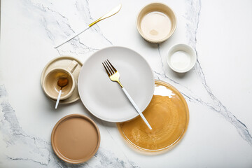 empty plates of different sizes with cutlery  and with cup  on white background 