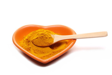 Turmeric (Curcuma) powder pile in shape heart, porcelain bowl and wooden spoon isolated on white  