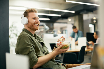 Happy freelance worker listens music while having lunch break at corporate office.