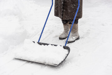 A woman with a big shovel removes the snow.