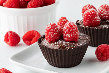 Close up of chocolate raspberry mousse filled cups on a small platter.