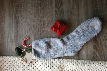 Fototapeta na wymiar Fluffy sock filled with small presents and knitted blanket. Flat lay.