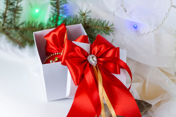 A Christmas gift decorated with a beautiful bow on a light background with a fir twig. Gifts, joy, surprise. Selective focus. the concept of Christmas and New Year.