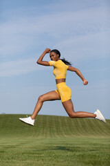 Fototapeta premium african-American woman in yellow fitness attire during working lunges in the air 0319