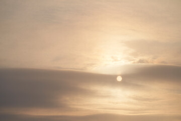 Winter cold sky. The sun is hiding behind a cloud. Its rays illuminate the sky. Snow is falling. Copy space.