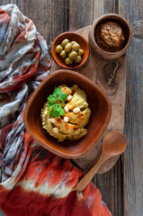 Bowl of hummus, traditional Jewish, Arabian, Middle Eastern food from chick-peas with dip tahini and olives on vintage wooden background. Close up, top view