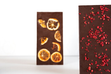 Organic chocolate bars with sublimated berries and orange slices on white background. Side view.
