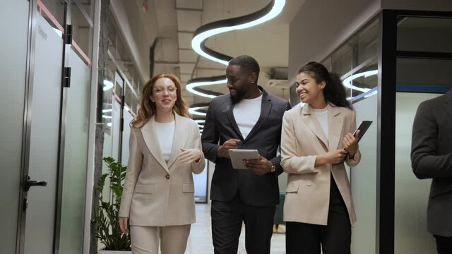 stylish employees in business suits walk in the office and communicate amicably. International team