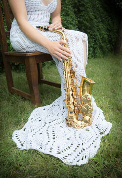 Saxof&oacute;n sostenido por mujer con vestido blanco tejido