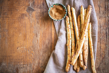 Italian grissini bread sticks with dried herbs on a wooden background.