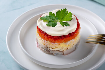 Traditional russian salad with herring and vegetables on a green background