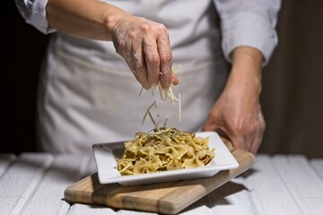 Sprinkling parmesan onto a pasta dish.
