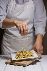 Putting parmesan cheese on bowtie pasta.