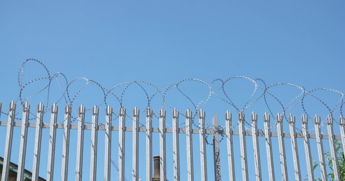 Security gate and barbed wired steel fence. Blue sky and barb wire metal gate.