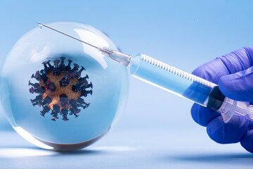 Mockup of virus in a glass sphere, and medical injection syringe with medicine or vaccine from COVID -19.