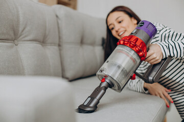 Woman doing house work with rechargeable vacuum cleaner