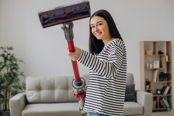 Woman doing house work with rechargeable vacuum cleaner