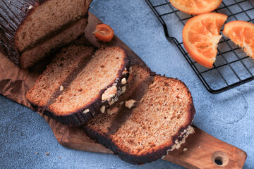 Gingerbread cake covered with chocolate and decorated with nuts, berries and orange on the wooden board. 