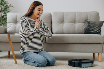 Woman relaxing while robot vacuum cleaner cleaning up the room