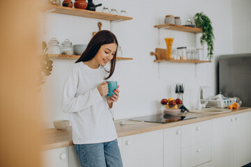 Woman drinking cup of coffee at kitchen at home