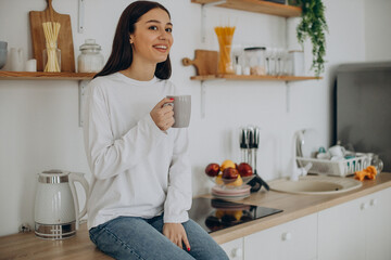Woman drinking cup of coffee at kitchen at home