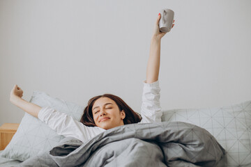 Woman awaking in her bed with a cup of coffee