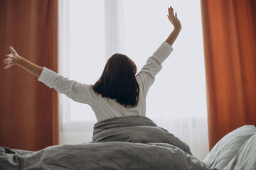 Woman awake stretching in her bed in the morning