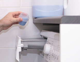 Mudchina, a Caucasian, middle-aged, pours bleach into the washing machine for washing clothes.