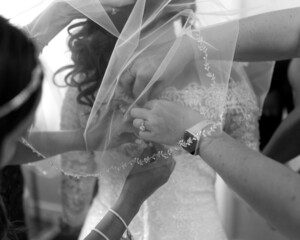 bridesmaids helping bride getting ready with dress on wedding day 