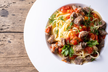 pasta with tomato sauce and meat on white plate and wooden background