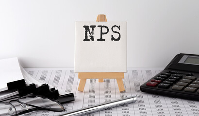 text NPS on easel with office tools and paper.Top view. Business concept