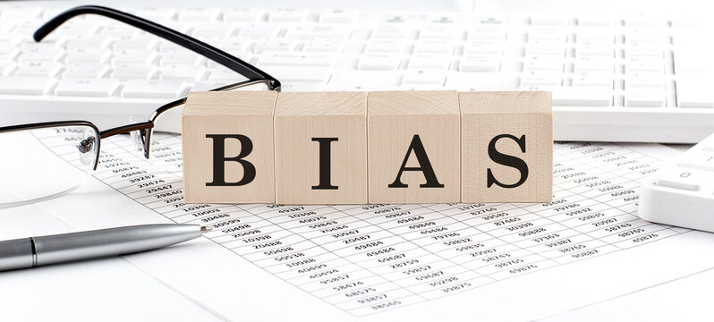 BIAS written on wooden cube with keyboard , calculator, chart,glasses.Business concept