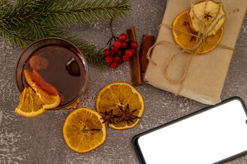 Mulled wine on a wooden table in a glass. And a mobile phone. Top view.