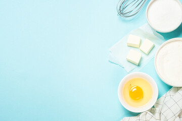 Baking ingredients at blue table. Flour, sugar, eggs and utensils. Top view with copy space.