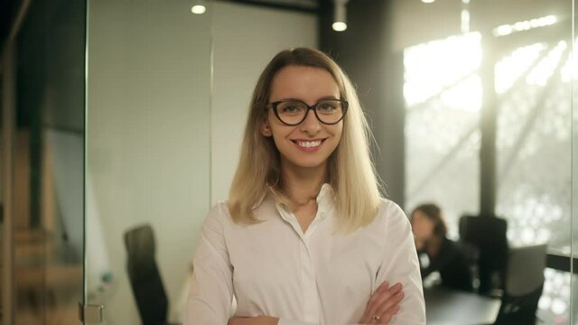 Portrait of smiling businesswoman looking to camera at coworking zone. Young attractive office worker at the office. High quality 4k footage