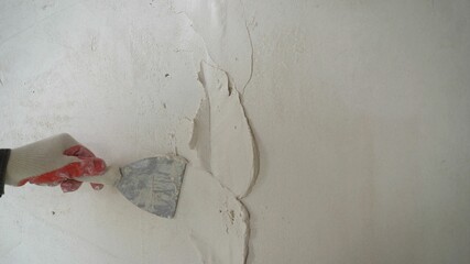 A worker man with the help of builders applies a layer of putty for the wall. The worker covers the...