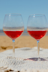 two glasses of red wine or juice at a picnic on the shore of a lake or ocean. a romantic date between two people in love. a basket with delicious food for a picnic and an outdoor dinner. beautiful