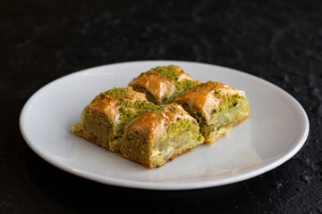 Pistachio baklava dessert on a dark background. Turkish sweet dessert concept. plate of pistachio...