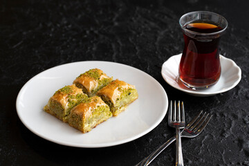 Pistachio baklava dessert on a dark background. Turkish sweet dessert concept. plate of pistachio baklava. sherbet sweet Mediterranean bakery. close up. selective focus.
