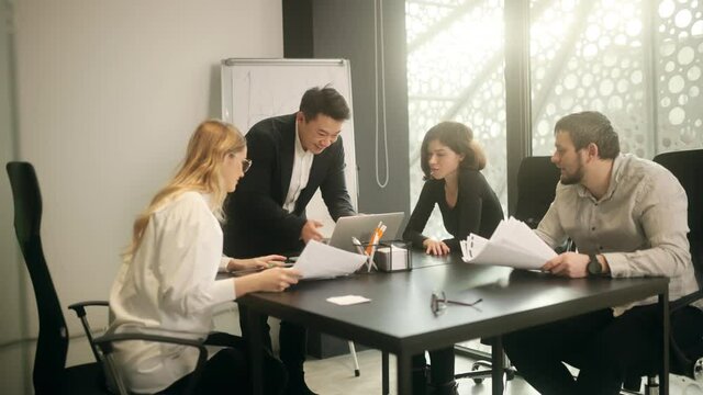 Portrait of happy asian businessman with his office workers enjoying success on laptop business centre. Closeup joyful young man reading good news on computer in slow motion.