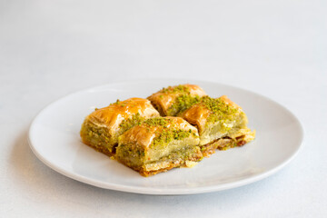 Pistachio baklava dessert on a white background. Turkish sweet dessert concept. plate of pistachio baklava. sherbet sweet Mediterranean bakery. close up. selective focus