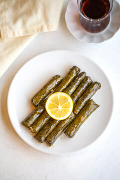Delicious dolma (sarma) stuffed grape leaves rice, white yogurt sauce. Stuffed grape leaves on white background. Lebanese dolma sarma on plate. Lebanon turkish greek middle eastern cuisine.