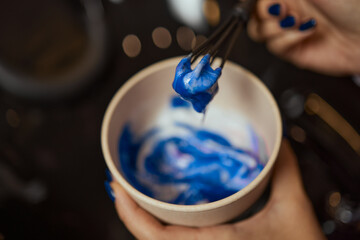 girl in white rubber protective gloves holding a brush in her hands and stirring hair dye close-up...