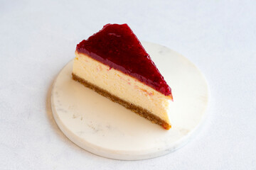 Cheesecake on white background. Greek sweet dessert concept. plate of sliced cheesecake. Cheesecake with raspberry gel filling. Mediterranean bakery. close up. selective focus. Horizontal view.